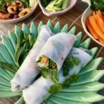 Summer rolls, a fresh delight! three rolls on palm plate with bowls close up
